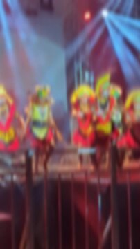 Blurry footage of the traditional Tumbu Tanah dance from West Papua performed on a night concert stage. Vibrant cultural movement with colorful costumes in an abstract, artistic atmosphere.