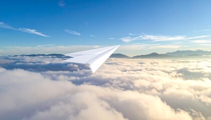 Obraz premium A white paper airplane soars above fluffy clouds under a bright blue sky with distant mountains