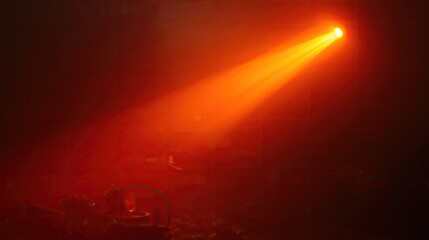 Bright orange spotlight illuminates a darkened space, highlighting the beams against a smoky backdrop.
