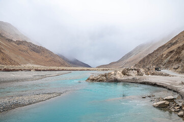 Obraz premium Turquoise blue river winding through the Himalayas, creating beautiful painterly curves. Stunning mountain landscape with vibrant water tones, natural beauty, and serene scenic flow like a painting