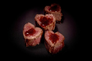 Heart-Shaped Slices of Tender Beef with Glossy Sauce on Dark Background