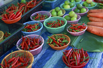 Colorful fresh chili pepper and lime in baskets at an outdoor market. vibrant display of spicy vegetable ingredients for healthy food and cooking at local stall