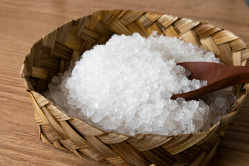 Sea salt in bamboo bowl with spoon on brown wooden background