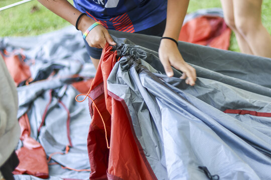 Closeup on person hand during tent setup for an outdoor camping activity. summer adventure promoting teamwork, survival skill, and connection with nature - Powered by Adobe