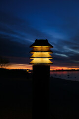Lamplight by seaside walkway in morning twilight. Vertical view, copy space. 