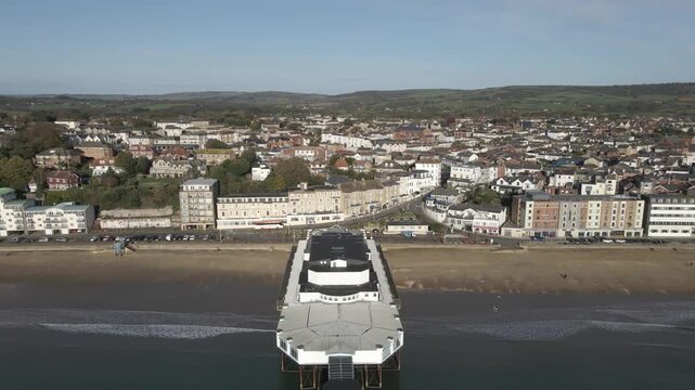 Aerial view of Sandown a seaside resort and civil parish on the south-east coast of the Isle of Wight, England. View of the Sandown pier with drone moving backwards over the pier.