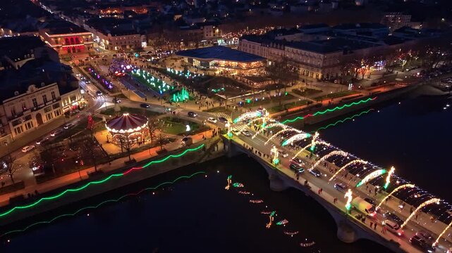 Pont Aristide Briand (Pont Neuf) illuminated for the Lumi&egrave;res Christmas festival, with Place du 11 Novembre decorated quays and reflections on Mayenne River in Laval, Mayenne, Pays de la Loire, France