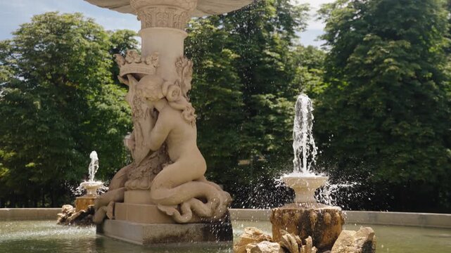 A carved stone fountain sprays water in Retiro Park Madrid Spain on a bright day