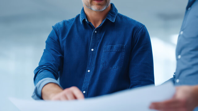Work discussion, business strategy, team planning meeting office with focused collaboration and calm confidence, blue denim shirt, professional hands review document, natural light, modern - Powered by Adobe