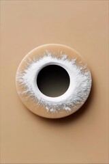 A top-down studio shot of a donut covered in powdered sugar, set against a beige background.
