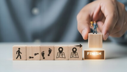Hand places miniature figure on finish block symbolizing achievement and success