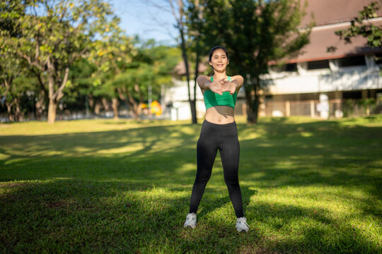 Young woman stretching arms outdoors in park - Powered by Adobe