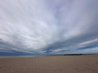 A serene and tranquil beach scene featuring sweeping clouds above, offering a peaceful and calming coastal ambiance