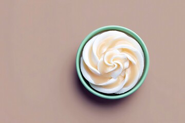 Overhead view of a bowl filled with whipped cream dessert, drizzled with a sauce, on a neutral background.