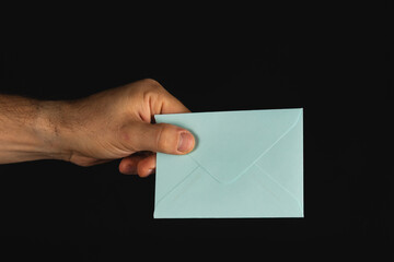 Hand holding a light blue envelope against a dark background