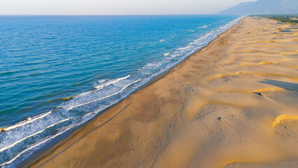 Gelemis, Turkey. Vast Patara Beach with tiny man walking, endless coastline to horizon, morning light and waves. Aerial View