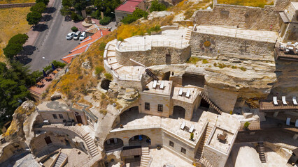 Urgup, Nevsehir, Turkey. Hotels at foot of cliff and luxury rooms carved into rock with traditional stone architecture.. Aerial View