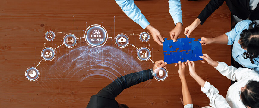 A group of professionals engaged in collaborative effort around a table, working with data-driven concepts and visual graphics to enhance business strategies. Trope