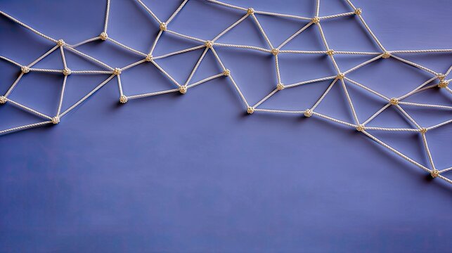 Overhead shot of a network of white ropes connected with knots on a blue background, representing connection and networking.