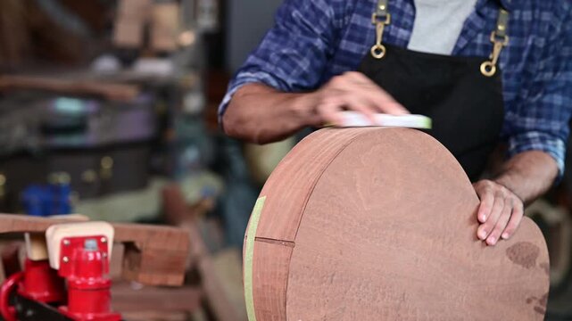 Luthier making top of guitar using traditional tools in workroom with manual tools, arts and craft concept.