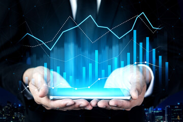 A businessman in a suit holds a smartphone displaying vibrant digital financial graphs. This image captures the essence of modern finance and digital analytics in a business context. Scalp