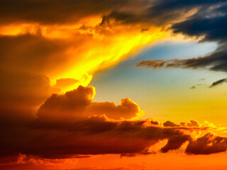 Fototapeta premium Dramatic sunset sky with golden and orange clouds, creating a vibrant and colorful atmosphere.