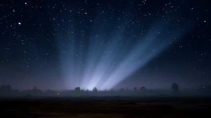 Obraz premium Starry night sky with dramatic light beams emerging from a fog covered horizon