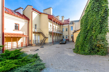 Sunny Residential Courtyard with Yellow Buildings and Ivy Wall