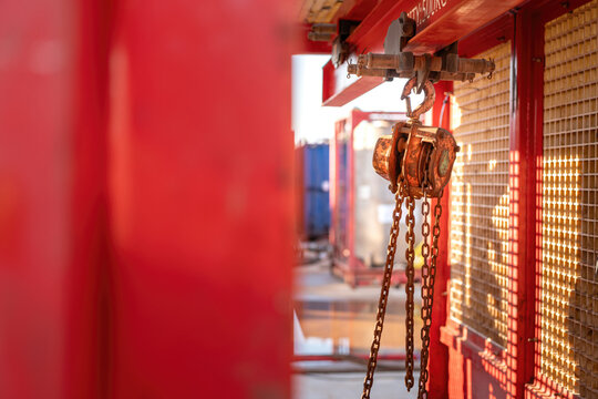 Metal pulley and hoist chain box, manual equipment using the lifting heavy object, it install on the beam of mobile toolbox. Industrial equipment object, close-up.