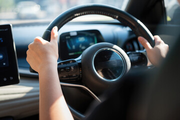 Naklejka premium Action of a driver is gripping on steering wheel to control the car during driving. Transportation mode with close-up and selective focus on the hand. 