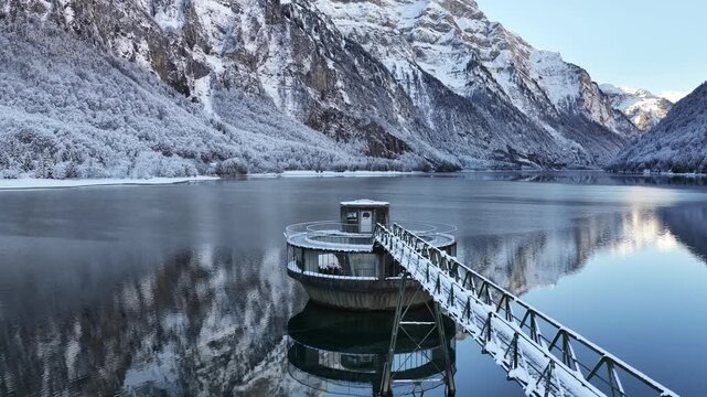 Snow covered water intake tower on Kl&ouml;ntalersee with winter alpine reflections