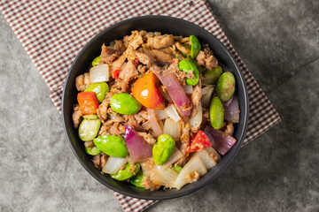 Top View of Spicy Thai Stir-Fried Pork with Stink beans in a Black Bowl