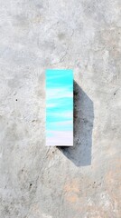 An abstract painting with blue and white colors, casting a shadow on a concrete surface. The image is taken from a top-down perspective.