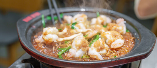 Woman tourist eating baked shrimp with glass noodles and garlic in restaurant. Popular foods for tourist eating in Chengdu, China. Chinese Asia and Sichuan foods concept