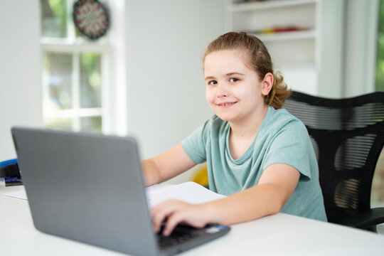 Kid using laptop for online studying at home. Child sitting at desk on virtual school lesson. Teenager learning with notebook and computer. Young student. Kids remote online class.