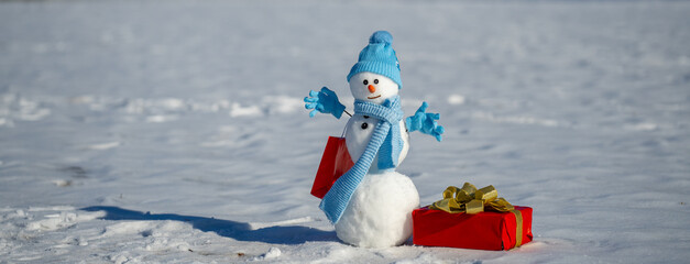 Snowman with Christmas gifts in a winter holiday sale scene. Snowman with Christmas present and red gift box in festive style. Snowman celebrating winter holidays with joyful greeting mood.