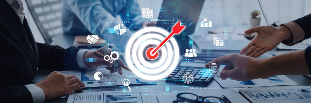 A modern office scene depicting business teamwork and strategy, featuring digital icons and target symbols that represent goal achievement and collaboration. Trope