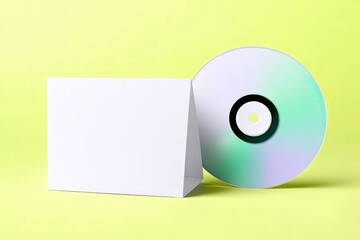A CD and its case are displayed against a bright yellow background, creating a clean and modern composition.