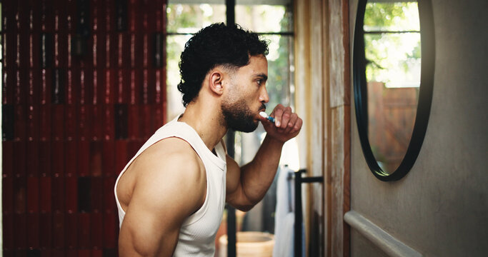 Man, profile or brushing teeth with mirror in bathroom for dental hygiene or fresh breath. Male person, cleaning and grooming with toothbrush or morning routine in home for mouth, oral and gum care