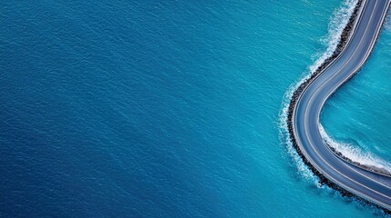 Aerial view of a road curving through the ocean, with blue water and a clear day.