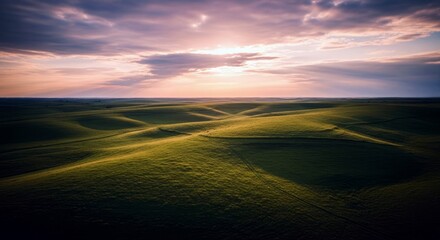 A scenic landscape of rolling green hills under a dramatic sunset sky. The sun's rays break through the clouds, illuminating the landscape.