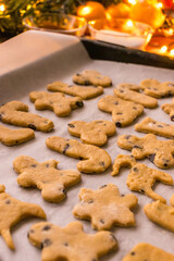 Unbaked Christmas cookies in festive shapes arranged on parchment paper. Holiday baking process with gingerbread dough, cookie cutters and warm seasonal kitchen atmosphere.