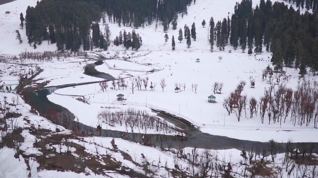 River Lidder flowing amidst the snowy landscape of the mountain valley during the winter season at Betaab Valley near Pahalgam in Jammu and Kashmir, India. Scenic view of river in winter at Kashmir. 