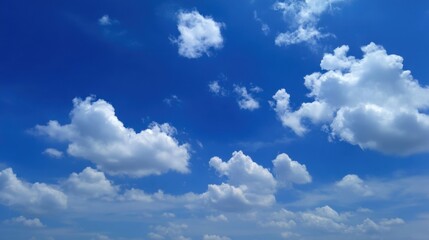 Fototapeta premium The sky is blue and full of clouds. The clouds are scattered throughout the sky, with some being larger and others smaller. Scene is peaceful and serene, as the clouds provide a sense of calmness