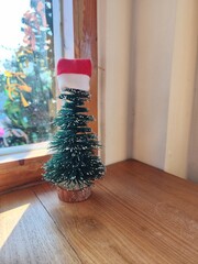 Mini Christmas Tree with Santa Hat by the Window in Cozy Morning Light