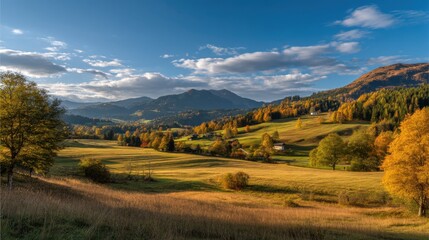 Naklejka premium Vibrant autumn colors fill the fields and trees as mountains rise in the background. Soft clouds drift across the blue sky creating a peaceful scene in the afternoon sun.