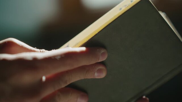 Hand holding a book, sunlight, introspective mood, exploration concept