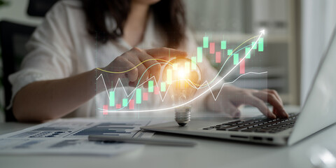 Business professional engages in financial analysis on a laptop while visualizing growth strategies through innovative light bulb concepts, highlighting creativity. Impute