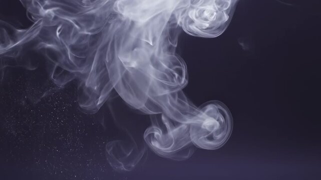 Extremely slow motion white wisps of translucent smoke drift and dissolve against a muted indigo background organic, mist, design