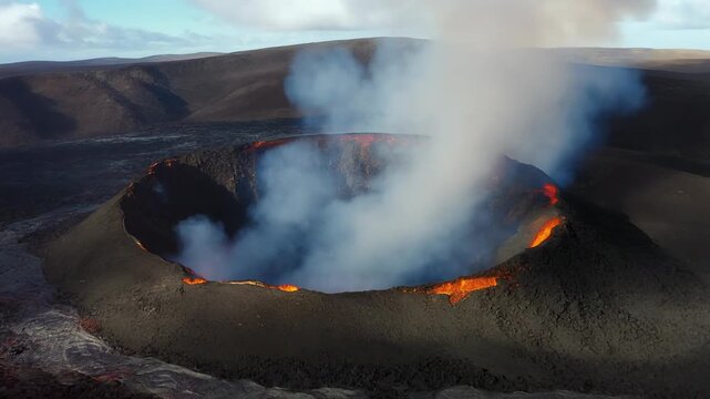 Active volcano crater spewing thick white smoke and molten lava glowing orange at sunset surrounded by volcanic rock landscape aerial drone footage